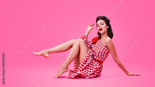 Konstfotografi Beautiful brunette in retro style sits on a pink background