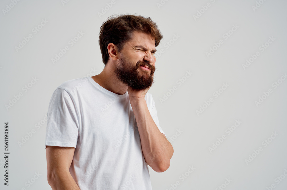 Obraz premium emotional man holding on to face pain in teeth light background