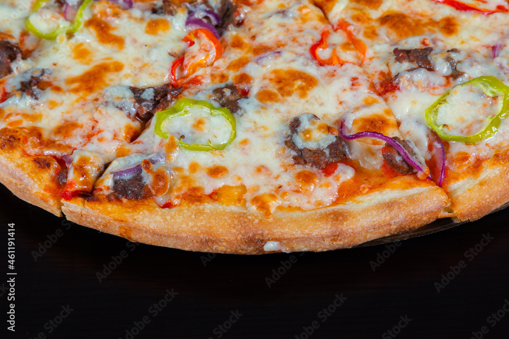 Slice of pizza with meat and vegetables on a black background