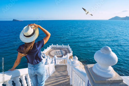 Carefree young tourist woman in sun hat enjoying sea view at Balcon del Mediterraneo in Benidorm, Spain. Summer vacation in Spain photo