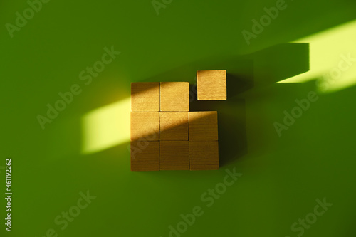 Nine wooden blocks in the form of the square on the green background with the natural shadows from the sunshine.