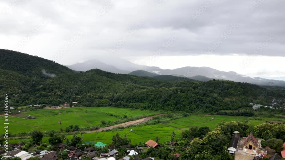 Aerial view Crane and tilt down shot over the hillside village with agriculture fields and rain fall on the mountain in Northern Thailand Aerial view Crane and tilt down shot over the hillside village with agriculture fields and rain fall on the mountain in Northern Thailand