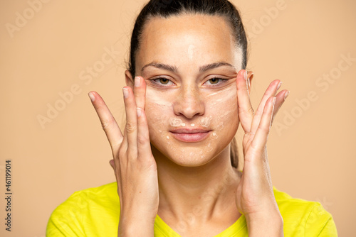 Closeup of young woman applies concealer on her face