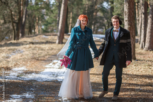 newlyweds in a wedding dress and suit are walking in the woods