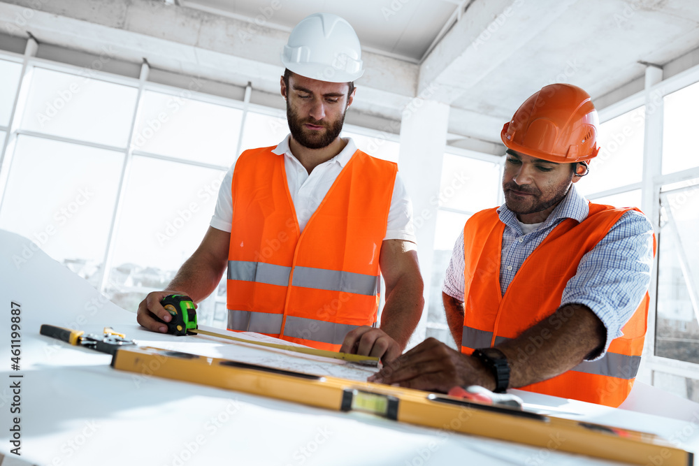 Two engineers man looking at project plan on the table in construction site