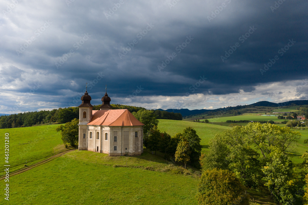Church of St. Margaret from the 18th century near Šonov. 
Beautiful church chapel in middle of fields in czech countryside broumovsko region with hills of broumov walls on background. Aerial view 