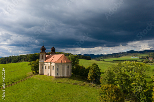 Church of St. Margaret from the 18th century near Šonov. Beautiful church chapel in middle of fields in czech countryside broumovsko region with hills of broumov walls on background. Aerial view 