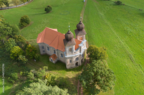 Church of St. Margaret from the 18th century near Šonov. 
Beautiful church chapel in middle of fields in czech countryside broumovsko region with hills of broumov walls on background. Aerial view  photo