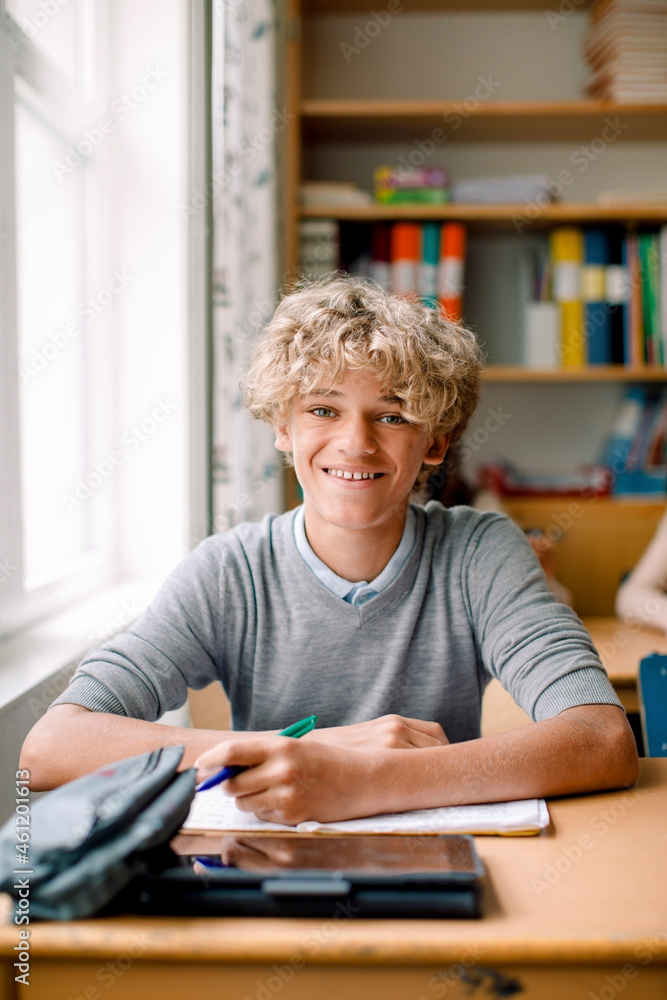 Smiling blond teenage boy at desk in classroom Smiling blond teenage boy at desk in classroom