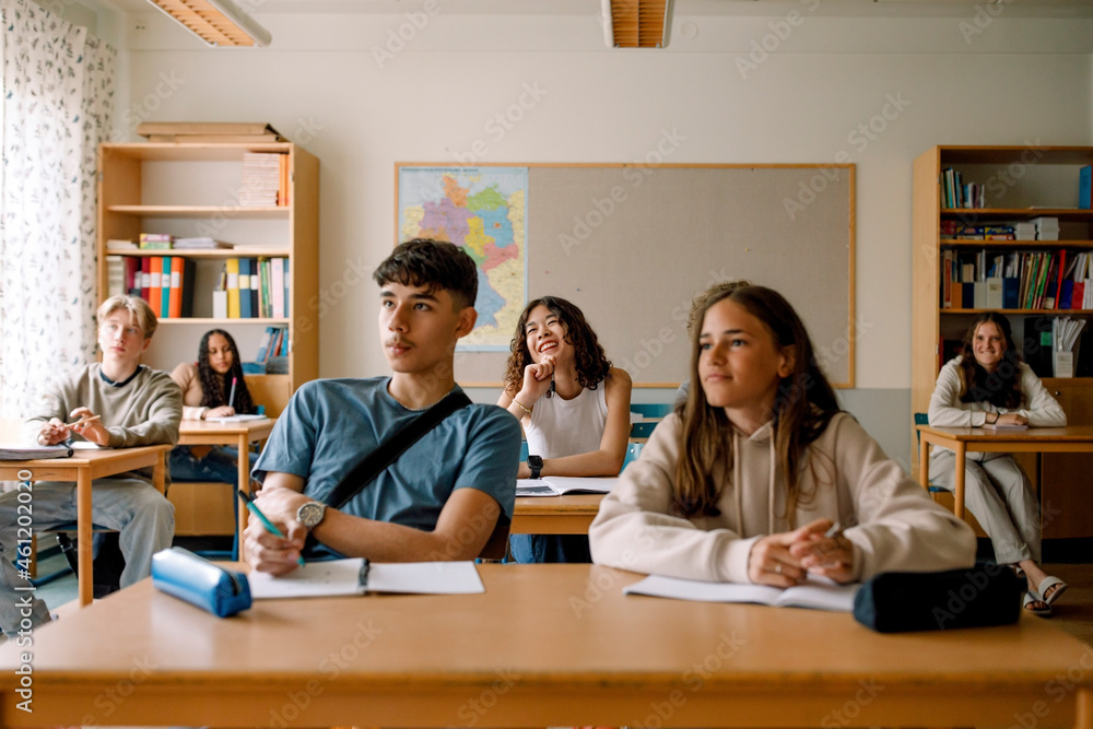 Smiling students studying at desk in classroom Smiling students studying at desk in classroom