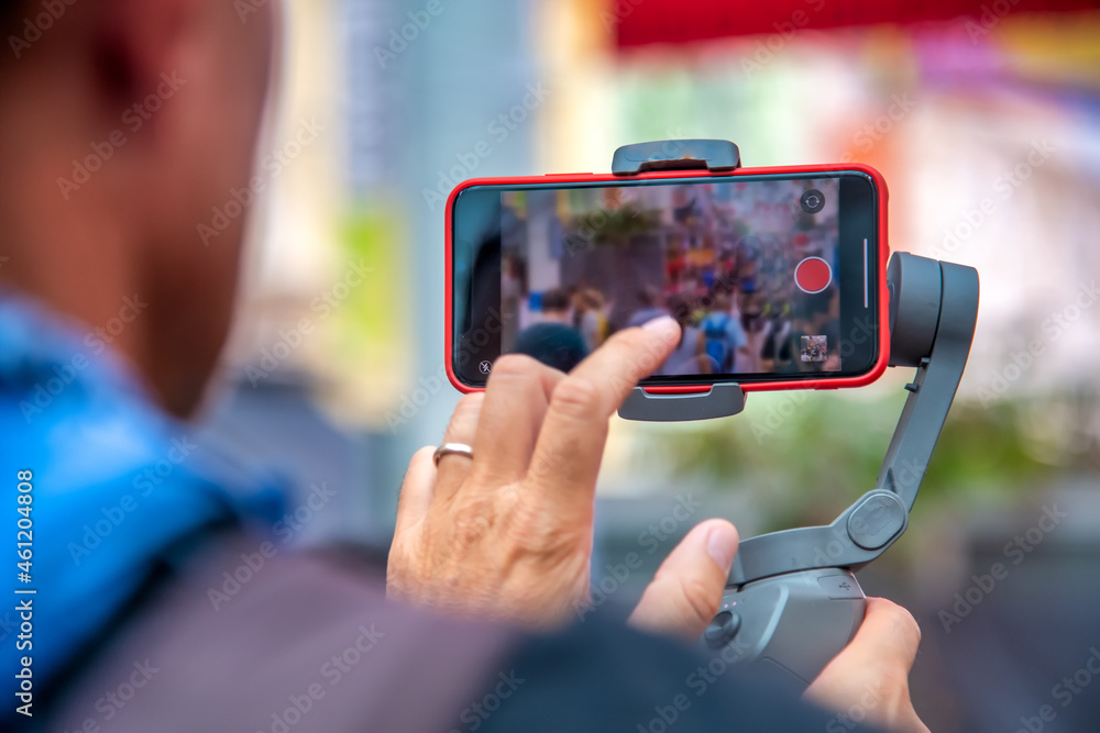 Man hands touching smartphone filming street scenes, city visit concept.