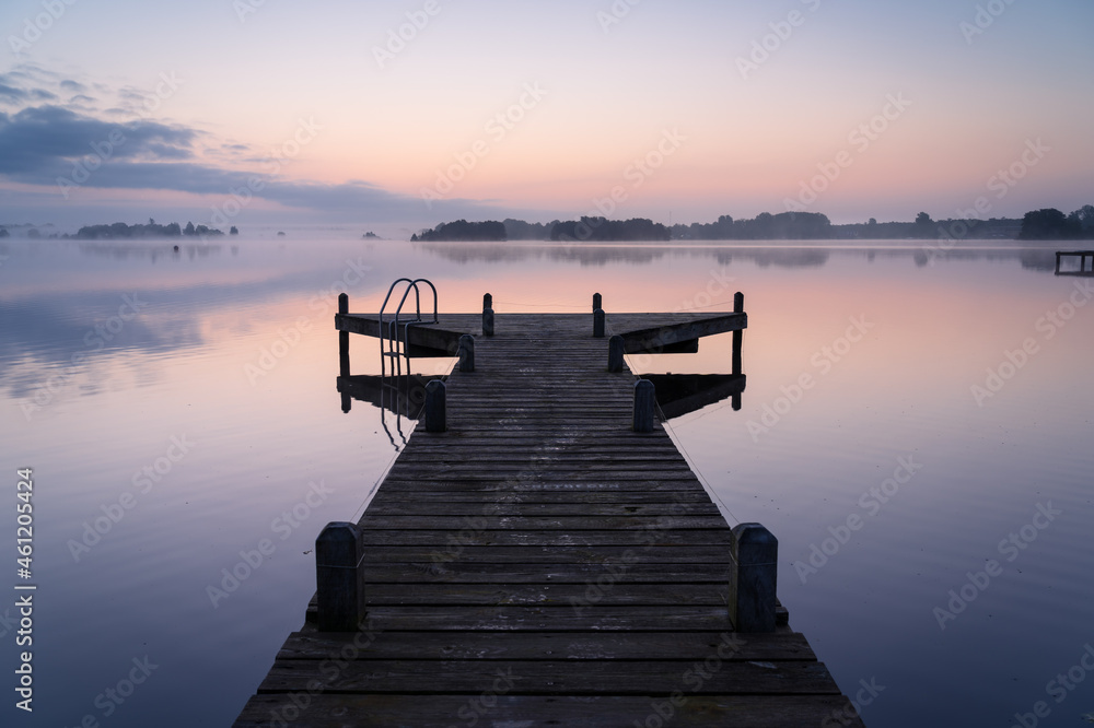 Obraz premium An empty jetty in a lake during a tranquil, foggy dawn.
