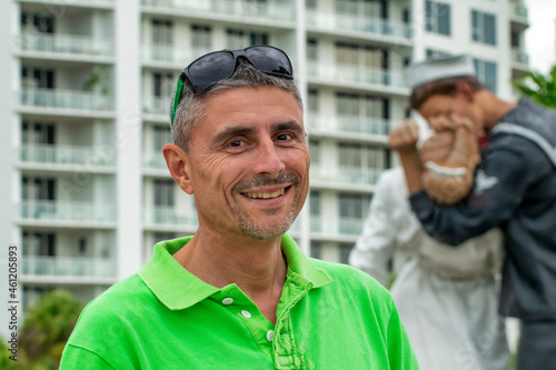 Happy smiling man in front of Unconditional Surrender Kiss Sculpture in Florida.