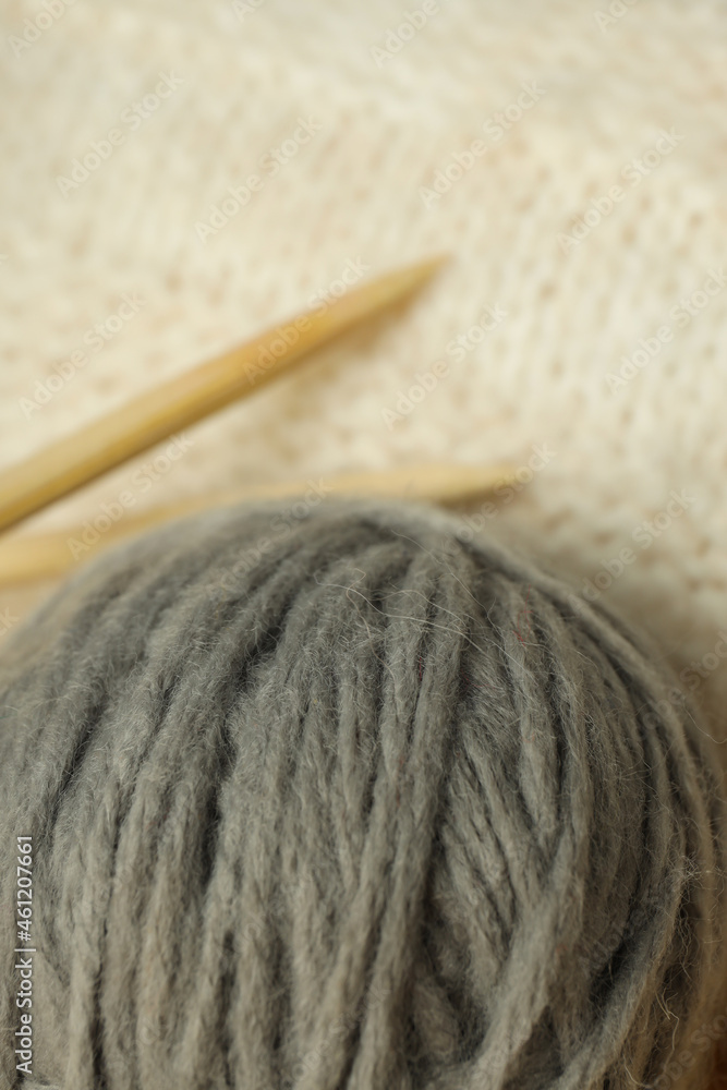 Gray ball of yarn on a light knitted background