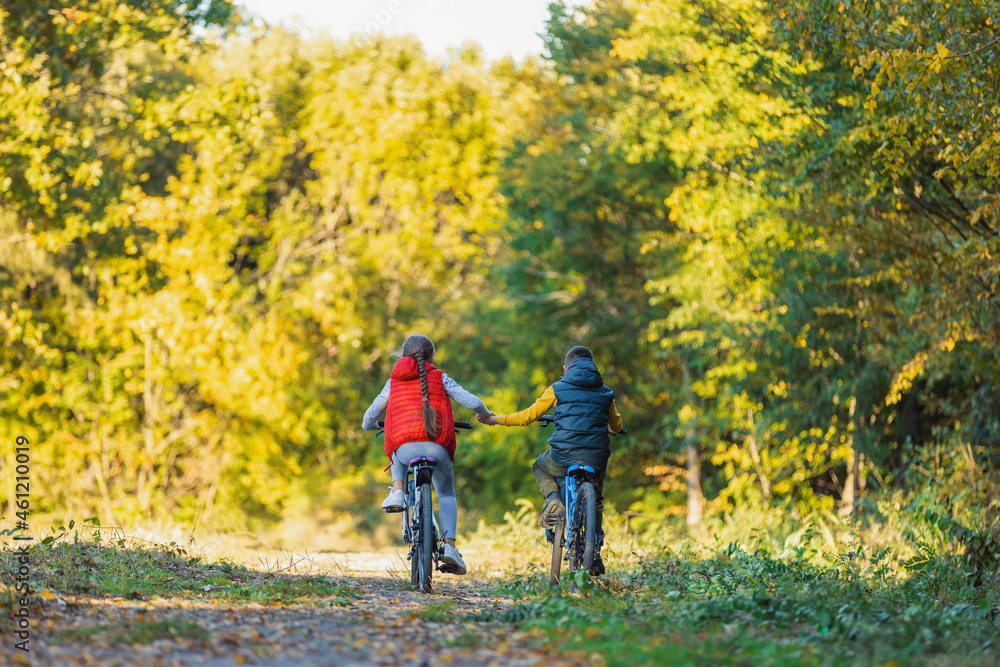 children ride a bike near the forest holding hands