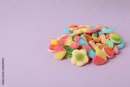 Gummy candies on violet background, space for text