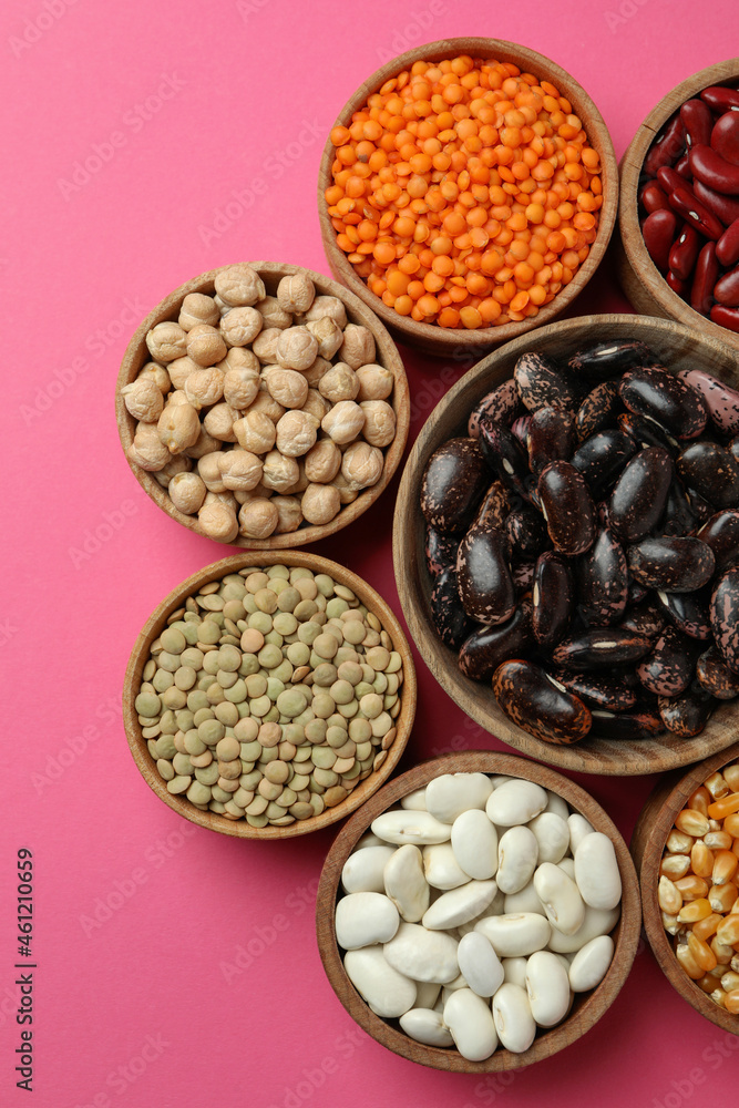 Flat lay composition with different types of beans on pink background