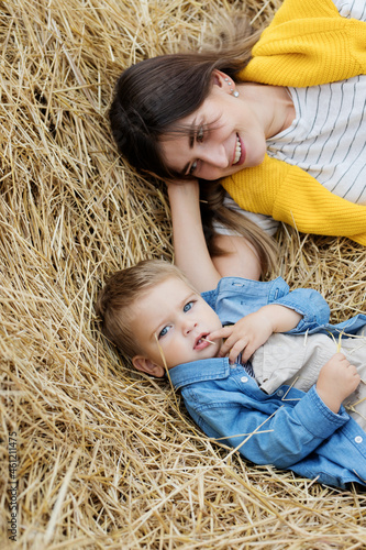 Beautiful  young mother and cute  son toddler are having fun on a haystack in the field  © Nastya_Gepp