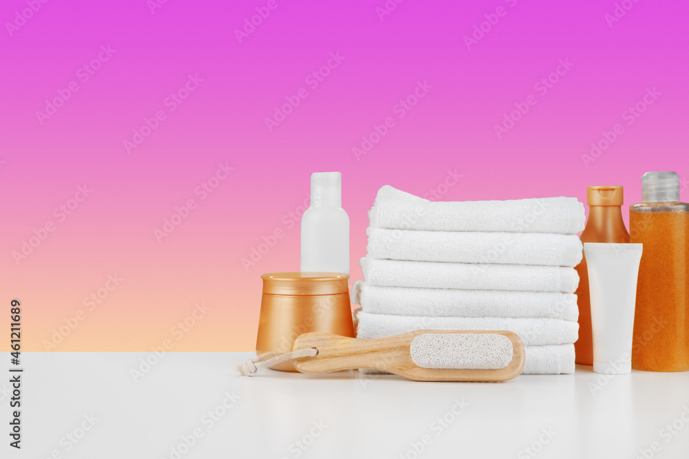 Pile of towels, bottles with shampoo on white table Pile of towels, bottles with shampoo on white table