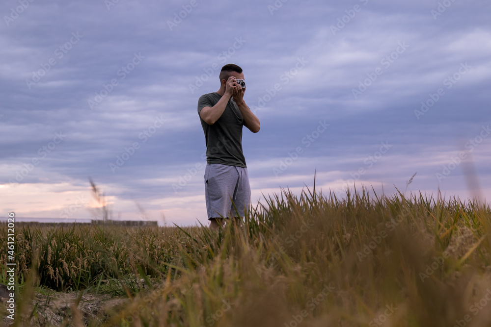 Man in a wheat field taking pictures with his analog camera Man in a wheat field taking pictures with his analog camera
