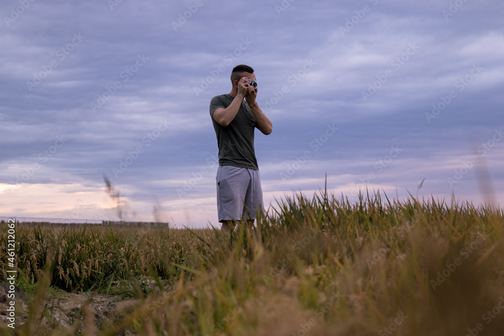 Man in a wheat field taking pictures with his analog camera Man in a wheat field taking pictures with his analog camera