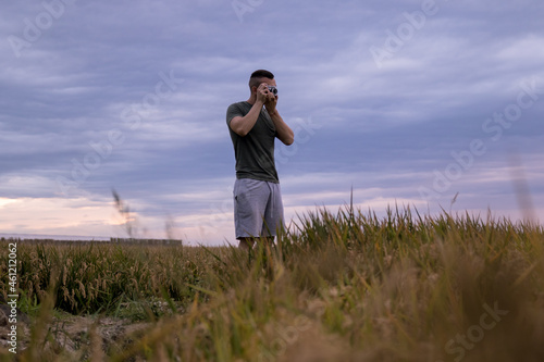 Man in a wheat field taking pictures with his analog camera