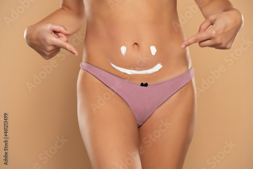 Pretty woman pointing on a smile drawn on her belly