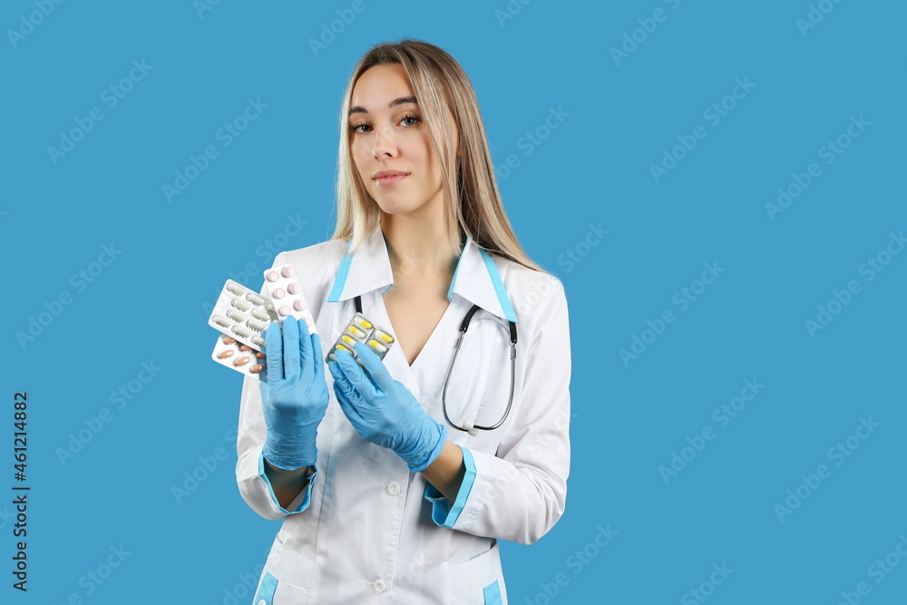doctor woman holds different pills packages close up on blue background, studio photo shoot. concept of medical treatment. doctor woman holds different pills packages close up on blue background, studio photo shoot. concept of medical treatment.