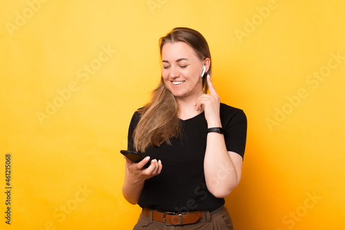 Beautiful woman is connecting to phone her new wireless ear phones.
