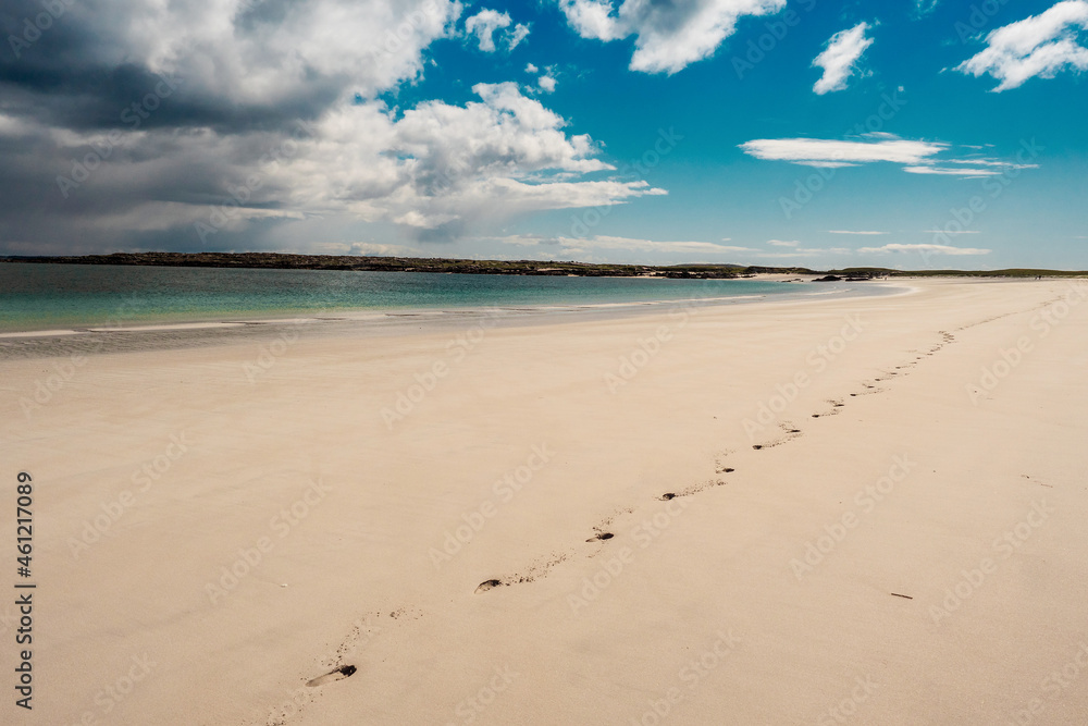 People footprints on a huge empty sandy beach, beautiful blue cloudy sky. Gurteen bay, county Galway, Ireland. Travel and tourism concept.