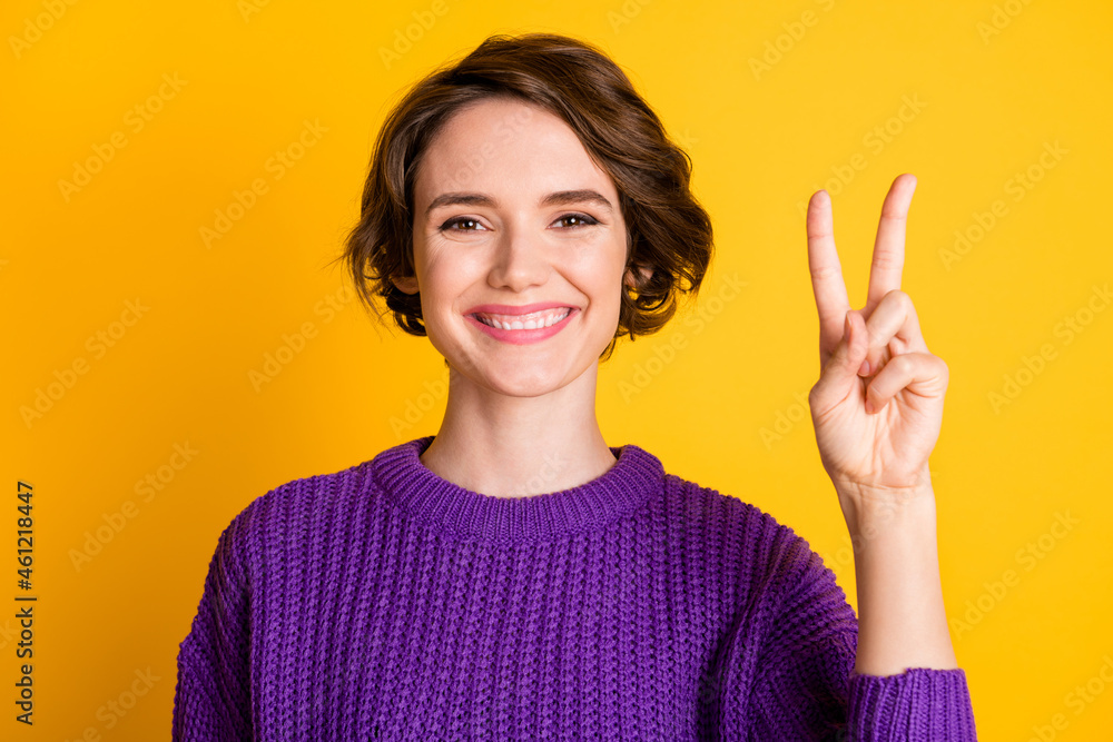 Portrait of attractive cheerful brown-haired girl showing v-sign good mood isolated over bright yellow color background Portrait of attractive cheerful brown-haired girl showing v-sign good mood isolated over bright yellow color background