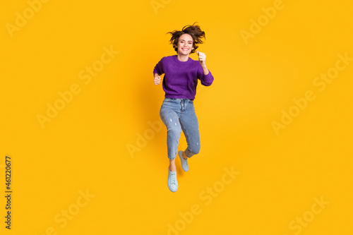 Photo portrait full body view of woman running jumping up isolated on vivid yellow colored background