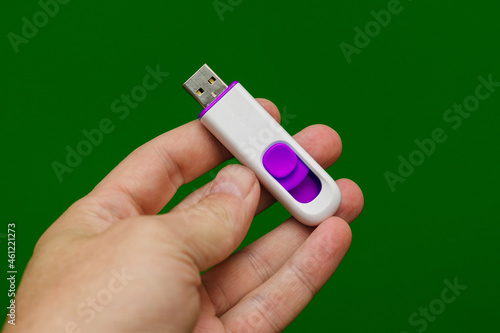usb flash drive white with purple in hand on a green background