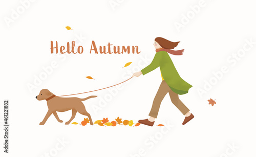 Woman in autumn clothing walking her dog with fallen leaves in the background
