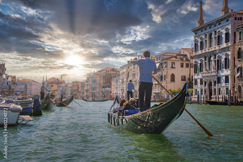 Venetian gondolier punting gondola through Grand canal waters of Venice Italy near Rialto bridge. © Aerial Film Studio