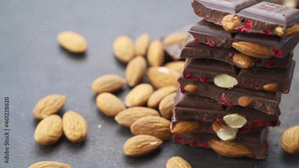 almond nuts falling on chocolate bar. Cooking chocolate bars with almonds, raspberries, handmade sweets. bars and pieces dark chocolate on black background. Confectionery craft on table almond nuts falling on chocolate bar. Cooking chocolate bars with almonds, raspberries, handmade sweets. bars and pieces dark chocolate on black background. Confectionery craft on table