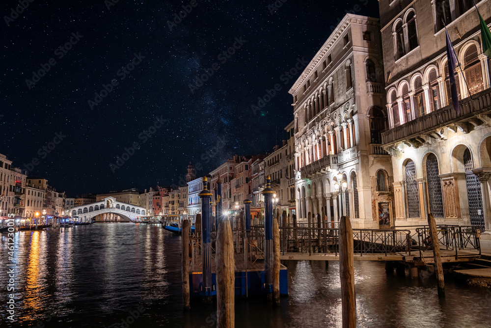 Beautiful view of Grand Canal and Rialto Bridge in Venice, Italy at night with beautiful stars and Milky way galaxy visible in the sky. Romantic style