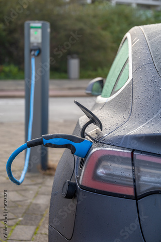 Tesla electric car charging batteries at plug in charge station