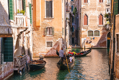Traditional gondolas on the narrow canal in Venice, Italy. Exploring beautiful Venice on water on a sunny day. © ingusk