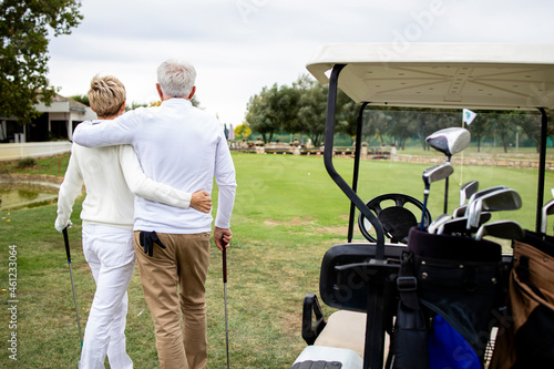 Senior couple holding together and enjoying recreational time in retirement by playing golf.