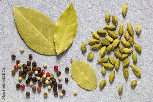 Aassorted colorful spices on grey concret background, flat lay, top view. Cardomon, bay leaf, cumin, pepper. photo