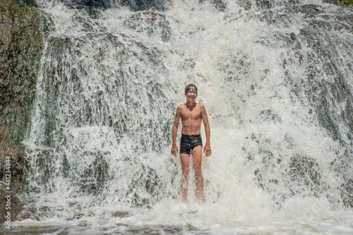 The joy of a boy bathing in a waterfall.