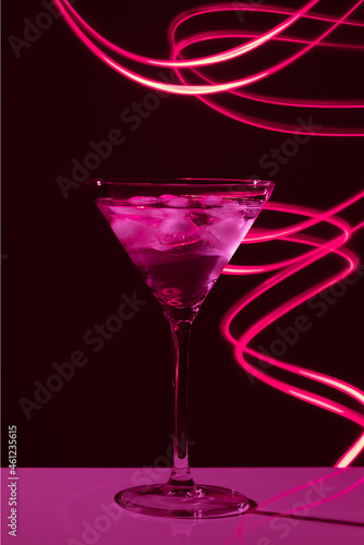 Martini glass with drink and ice against creative lighting