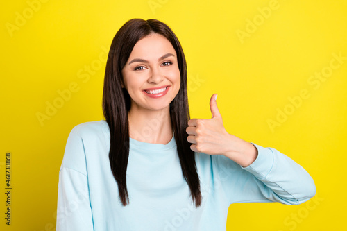 Photo portrait woman smiling happy showing thumb-up sign wearing jumper isolated vibrant yellow color background