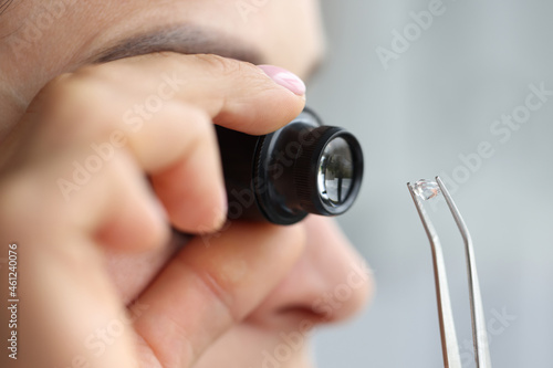 Woman looks through magnifying glass at precious stone photo