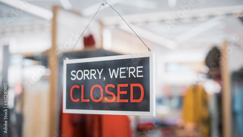 Shot of a Sign "Sorry, we are Closed" on a Glass Door of a Stylish Clothes Store. Blurred background of a Shop, Supermarket, Bar or another Company, Business. Pandemic Concept.