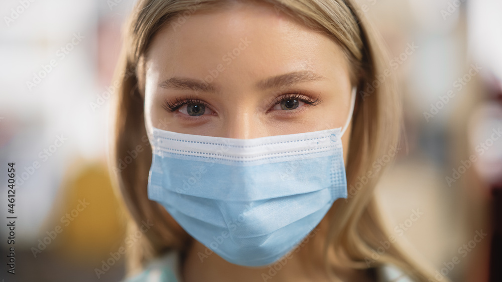 Close Up Portrait of a Beautiful Young Woman with Blonde Hair and Green Eyes Wearing Protective Medical Face Mask. Female Practicing Social Distancing, Quarantine. Close Up Portrait of a Beautiful Young Woman with Blonde Hair and Green Eyes Wearing Protective Medical Face Mask. Female Practicing Social Distancing, Quarantine.