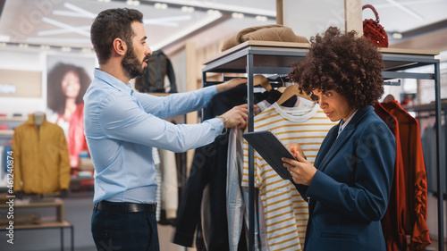 Clothing Store: Businesswoman Uses Tablet Computer, Talks to Visual Merchandising Specialist, Collaborate To Create Stylish Collection. Small Business Fashion Shop Sales Manager Talks to Designer.