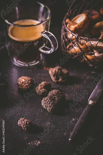 Black truffle on dark kitchen table with black coffee and mushrooms