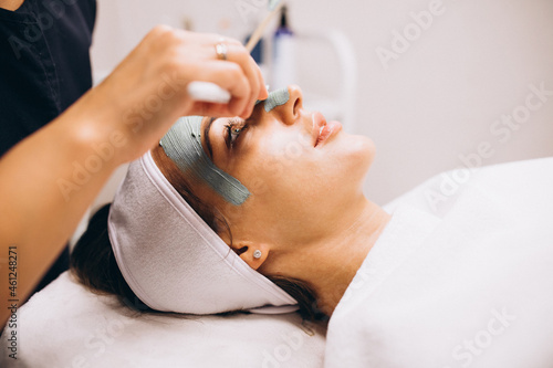 Cosmetologist applying mask on a face of client in a beauty salon